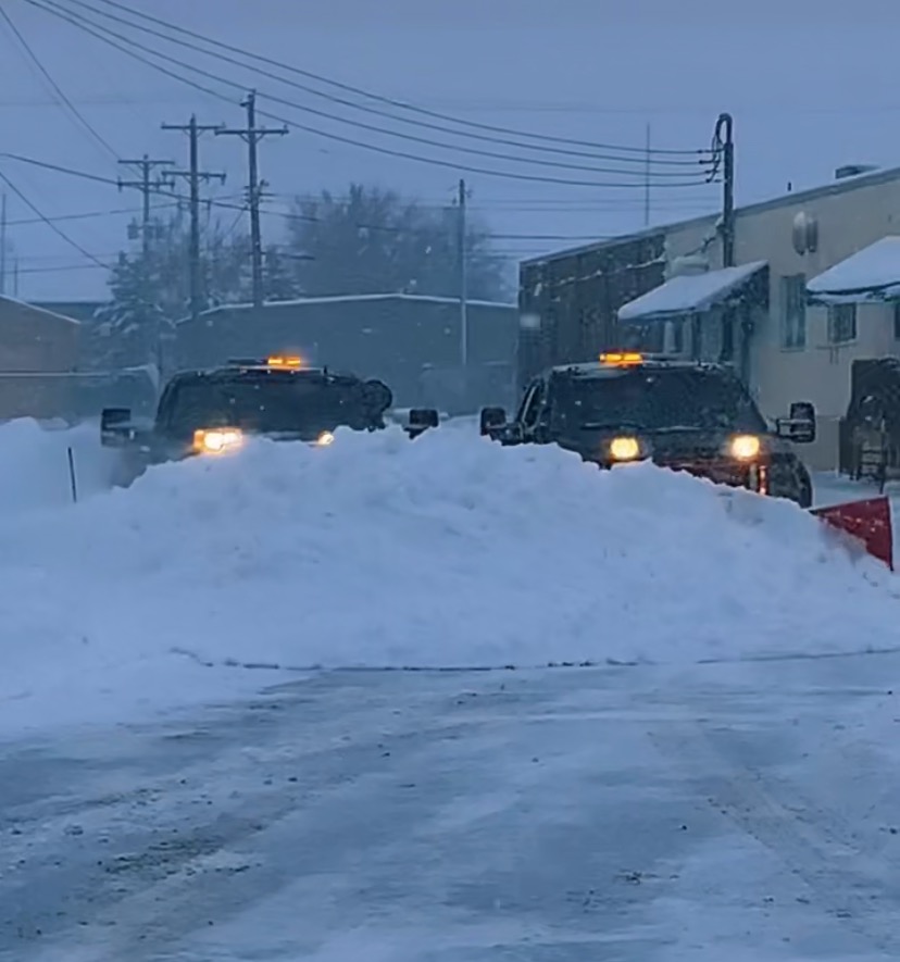 Two Sharp Image plow trucks working through a blizzard at dusk