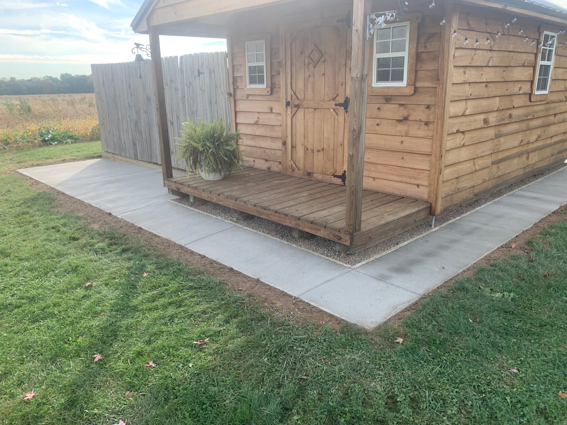 Finished concrete pad wrapping a cedar shed
