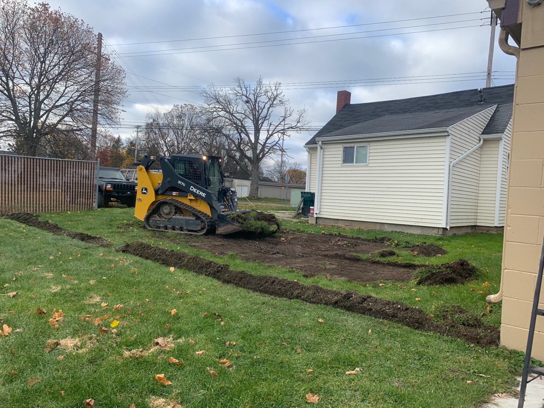 John Deere 317G skid steer grading a residential yard